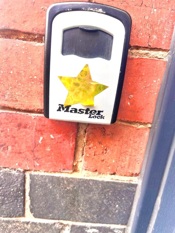 Master Lock key storage box mounted on red brick exterior wall