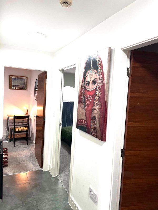 Hallway with white walls, wooden doors, framed artwork, and view into adjacent rooms