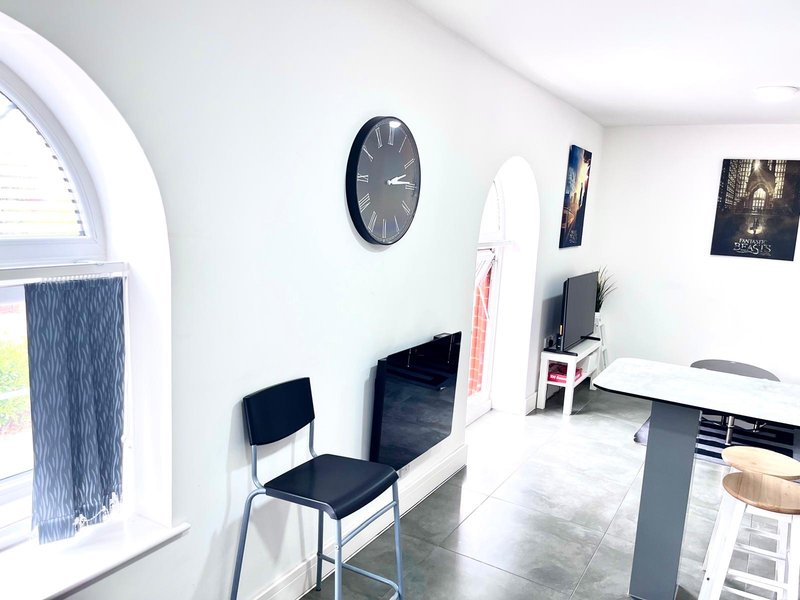 Modern white office space with desk, black chairs, wall clock and large arched window