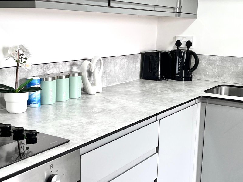 Modern kitchen countertop with white cabinets, marble worktop, and kitchen accessories