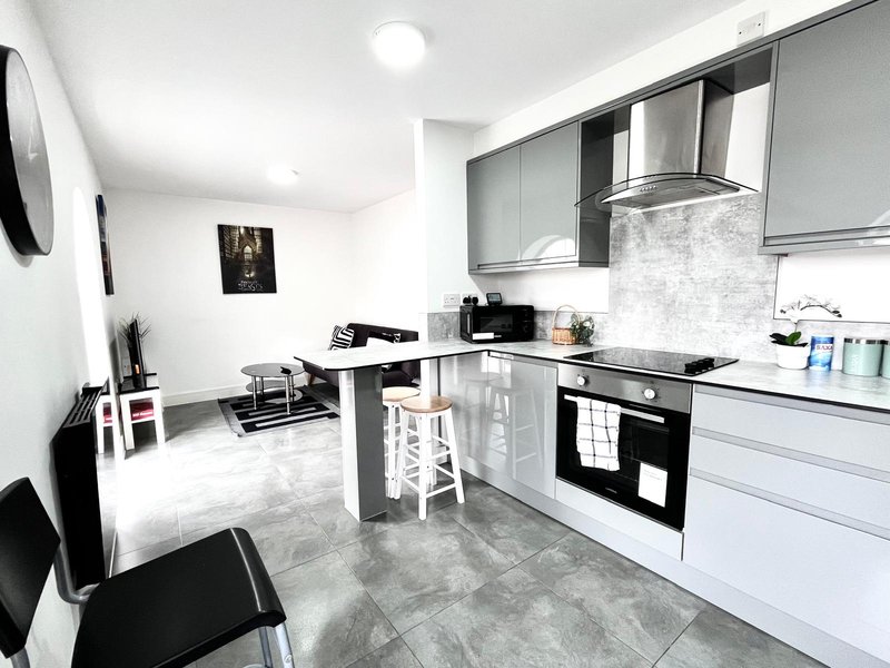 Modern kitchen with white cabinetry, black appliances, breakfast bar and dining area
