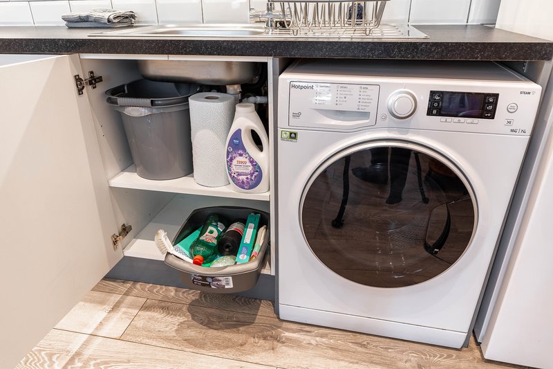 Convenient laundry area with a washing machine and storage space to make longer stays more comfortable.