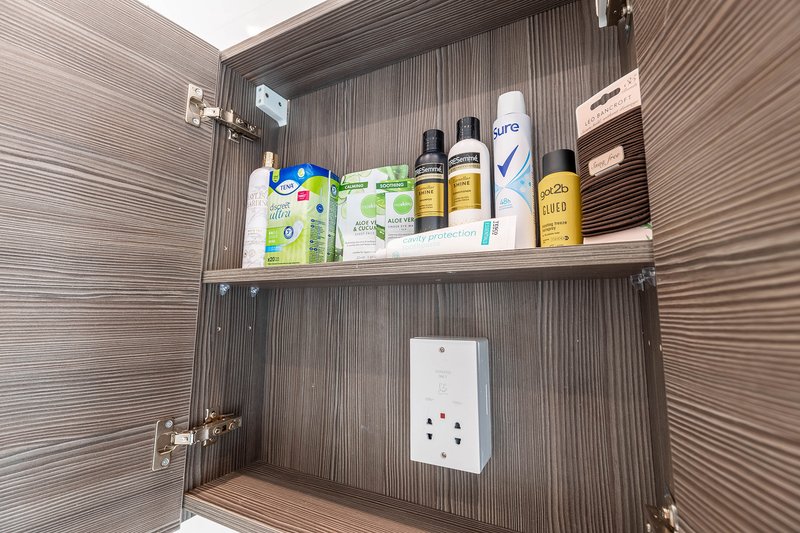 Bathroom cabinet interior with toiletries, cleaning products, and personal care items on shelves