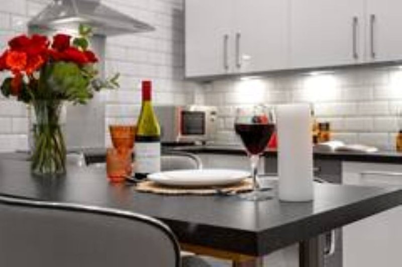Modern kitchen with black island, white cabinets, wine bottles, flowers and place setting
