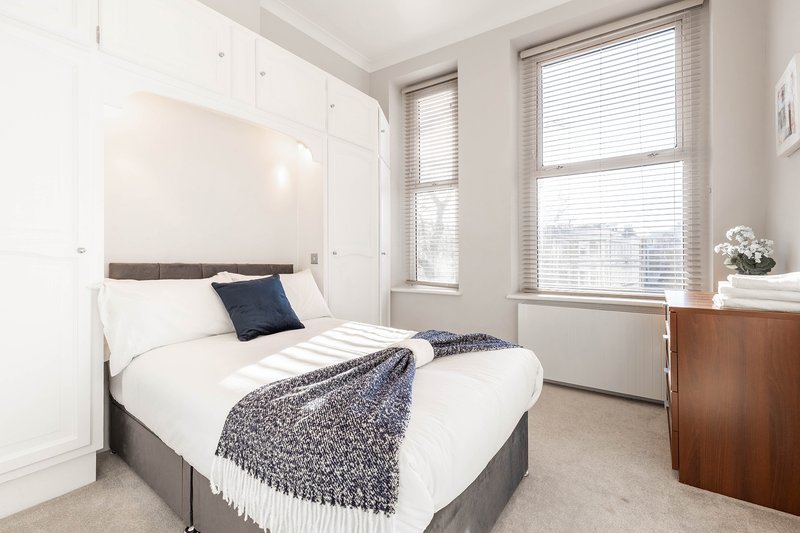 Relax in a spacious double bedroom featuring a comfortable bed and modern furnishings for a restful night's sleep. Bright and airy, it's the perfect space to unwind after a day exploring London.