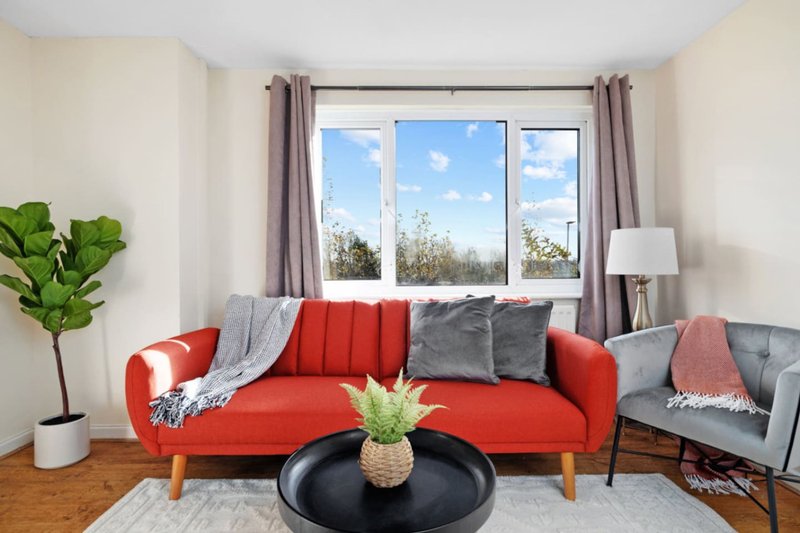 Bright living room with red sofa, gray armchair, coffee table and large windows