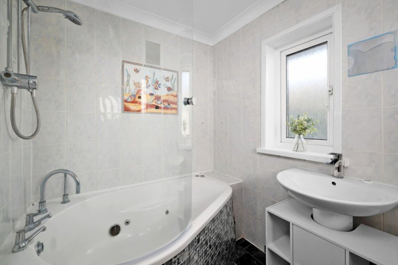 Modern bathroom with bathtub, shower, white sink and window with flowers