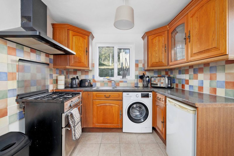 Kitchen with wooden cabinets, colorful tile backsplash, gas range and washing machine