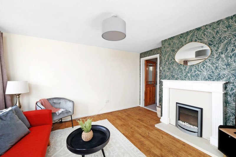 Modern living room with fireplace, wooden floor, red throw, and patterned wallpaper