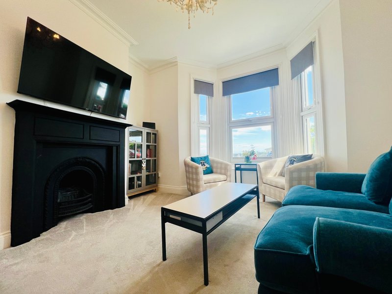 Bright living room with fireplace, TV, blue velvet sofa and bay windows overlooking mountains