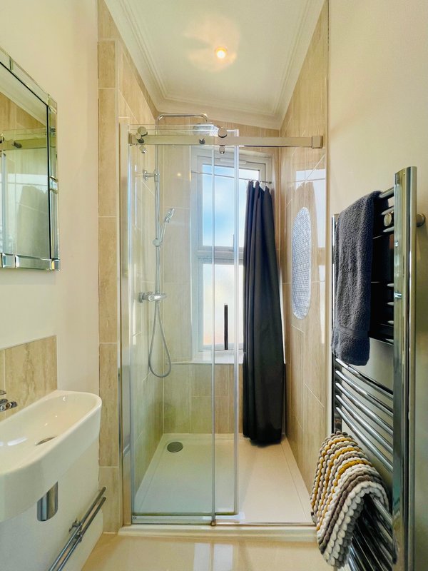 Modern bathroom with walk-in shower, sink, heated towel rail and window
