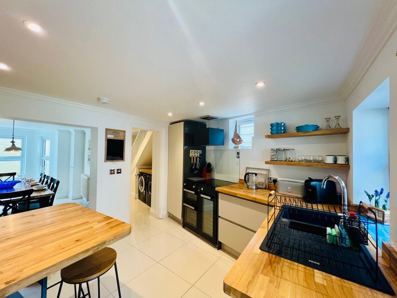 Modern kitchen with wooden countertops, black appliances, open shelving and dining area