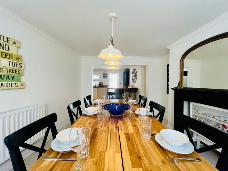 Dining room with wooden table, black chairs, pendant light, and place settings