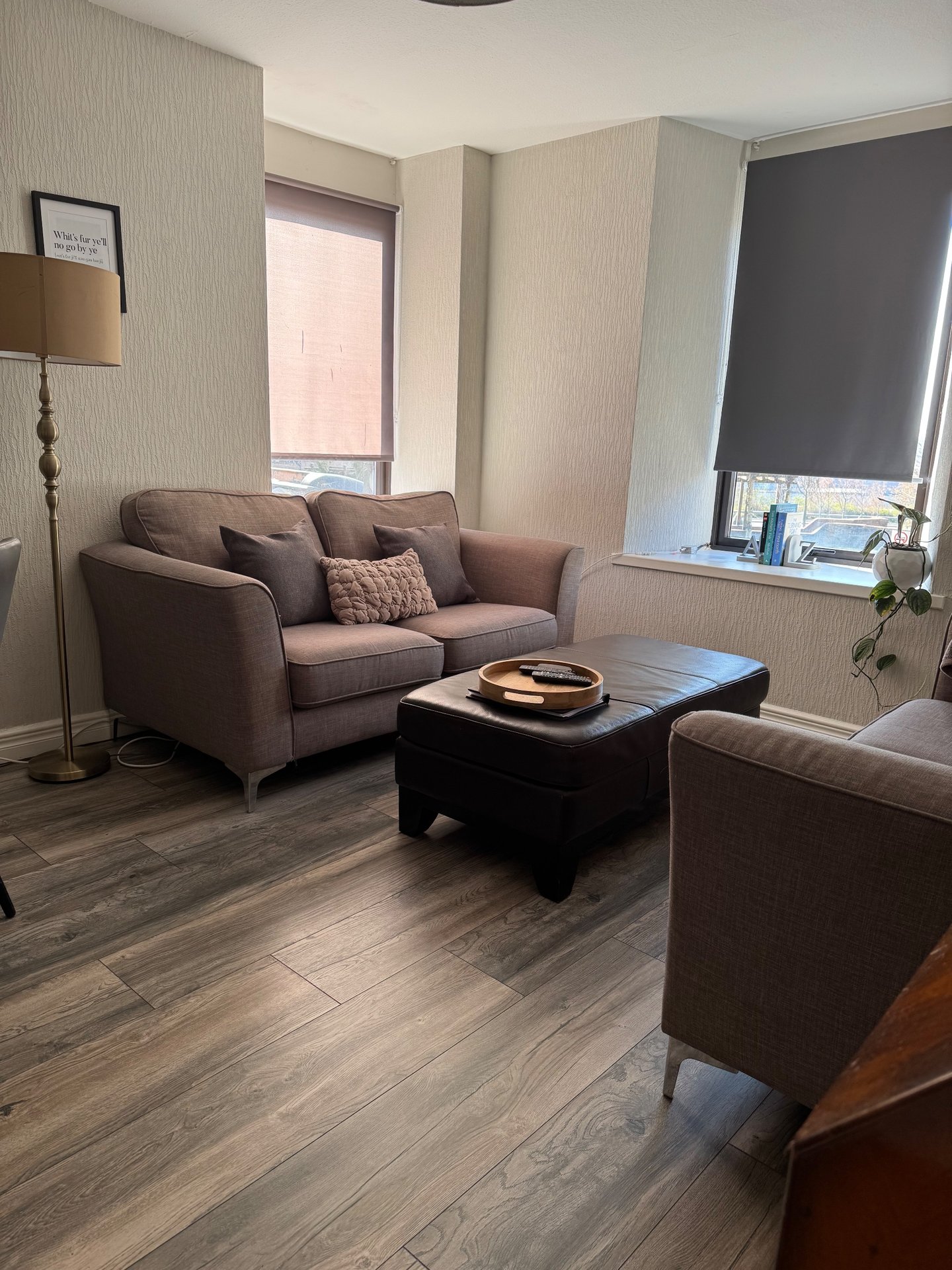 Living room with brown sofa, black coffee table, floor lamp and windows with blinds