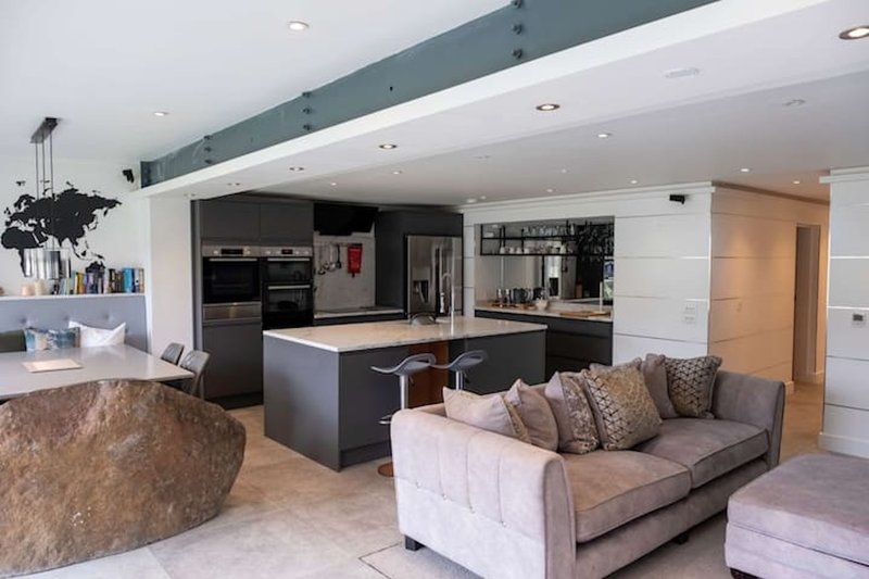 Open-plan living and kitchen space with island, sofa, and modern appliances