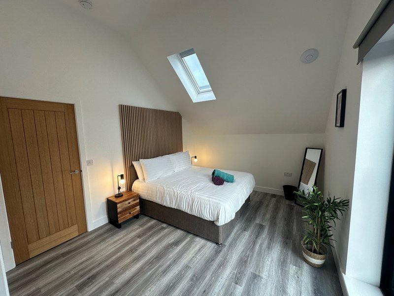 Bright attic bedroom with double bed, wooden wardrobe, skylight and potted plant