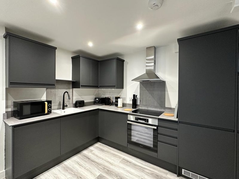 Modern kitchen with dark gray cabinetry, stainless steel appliances, white countertops, and recessed lighting