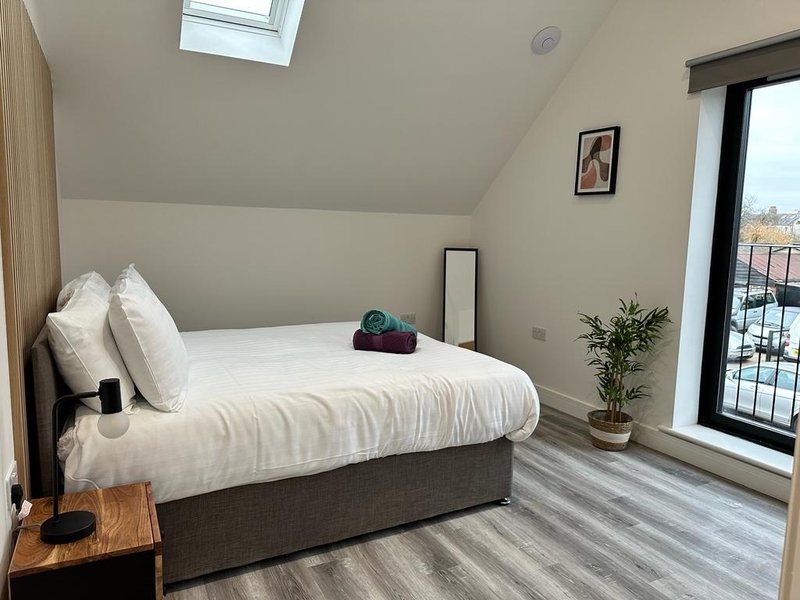 Modern bedroom with double bed, white pillows, wooden nightstand, and skylight window