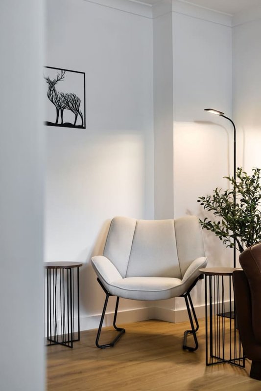Modern living space with cream upholstered chair, side tables, floor lamp and wall art