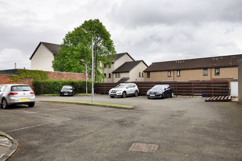 Residential property exterior with driveway, parked cars, and surrounding houses