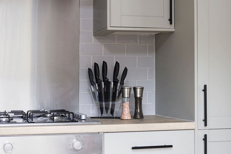 Modern kitchen counter with gas hob, knife block, and white subway tile backsplash