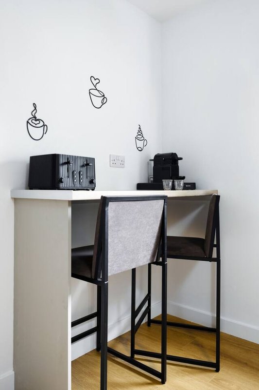 Minimalist desk workspace with black chair, wall decals, and desk lamp