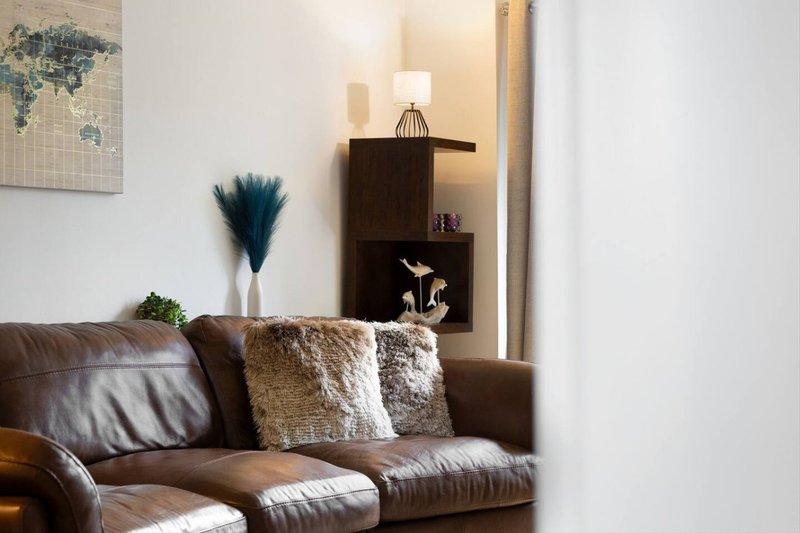Brown leather sofa with decorative cushions, lamp, and wall art in modern living room