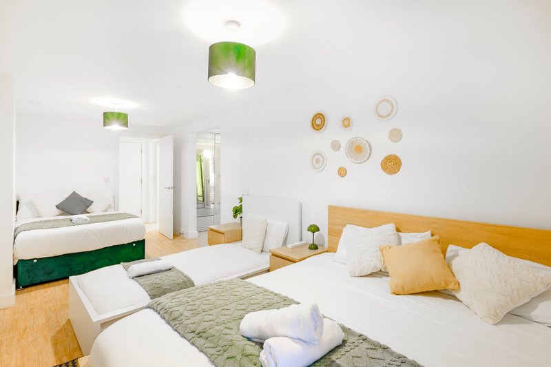Modern bedroom with two beds, green headboards, white walls and decorative plates