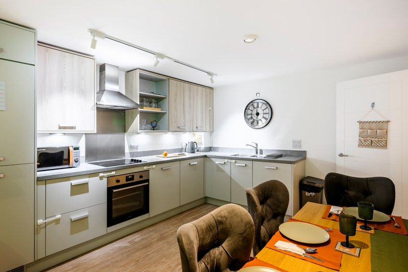 Modern kitchen with cream cabinets, stainless steel appliances, and dining table with chairs