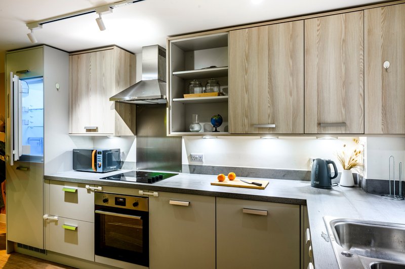 Modern kitchen with wooden cabinetry, stainless steel appliances, white countertop and open shelving