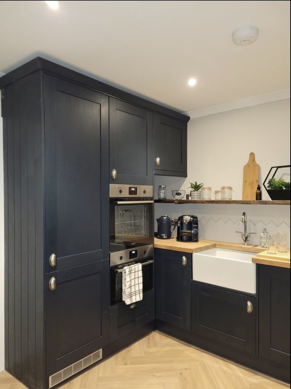 Modern kitchen with dark cabinetry, wooden countertops, stainless steel appliances and white sink