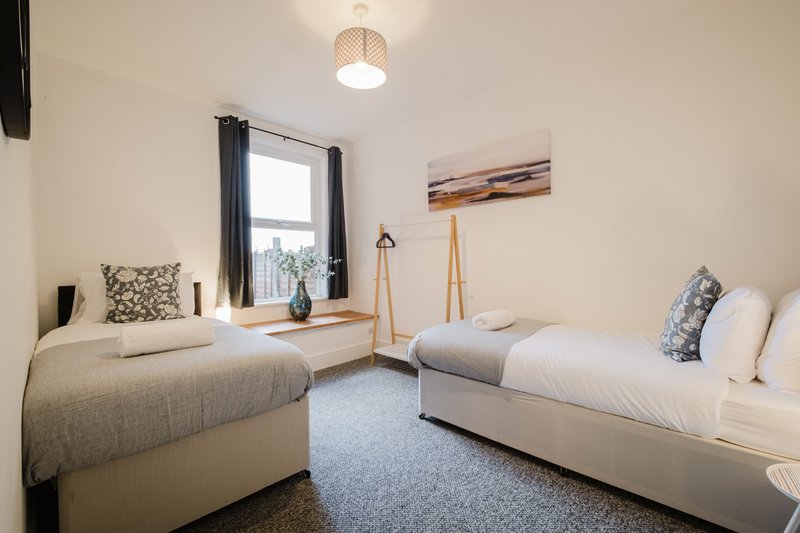 Twin bedroom with two single beds, window, pendant light and framed wall art