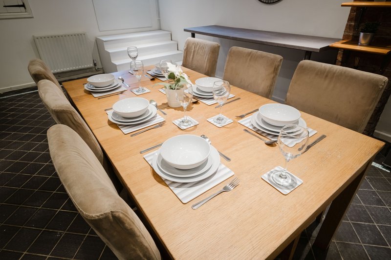 Dining room with wooden table set for six, upholstered chairs, place settings and glassware
