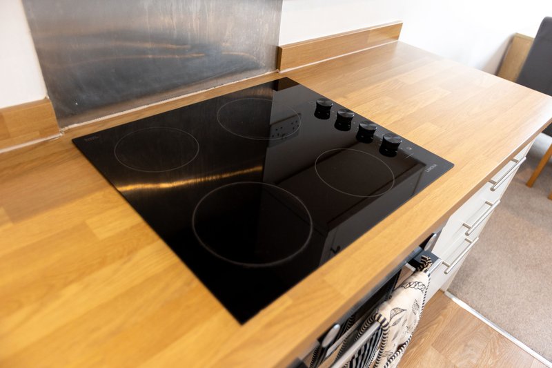 Modern kitchen with wooden countertop, built-in electric hob and stainless steel oven