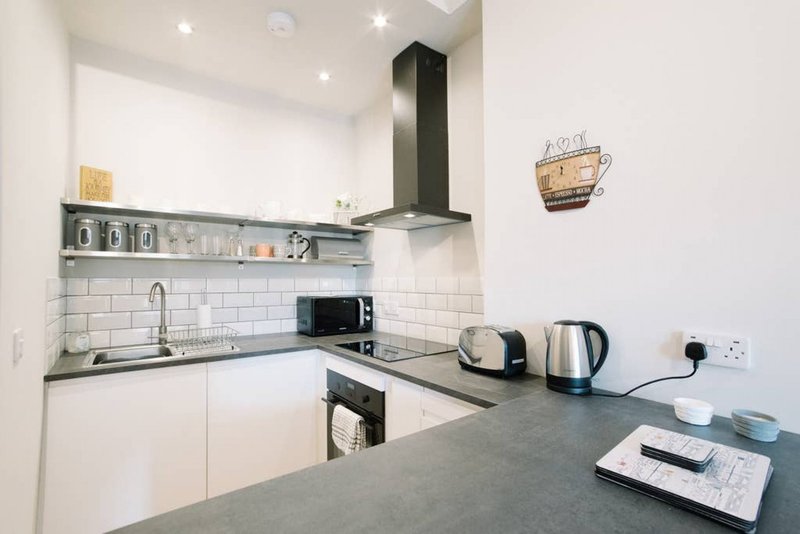 Modern white kitchen with black countertop, stainless steel appliances and subway tile backsplash