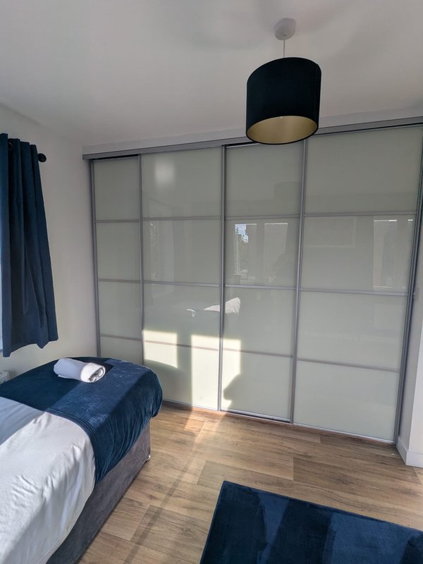 Bedroom with double bed, sliding wardrobe doors, wooden floor and pendant light
