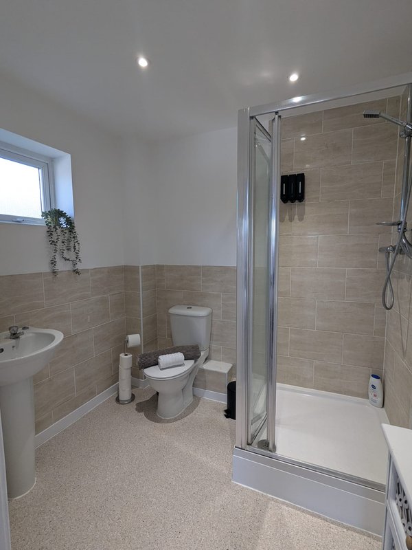 Modern bathroom with toilet, sink, shower enclosure and tiled walls