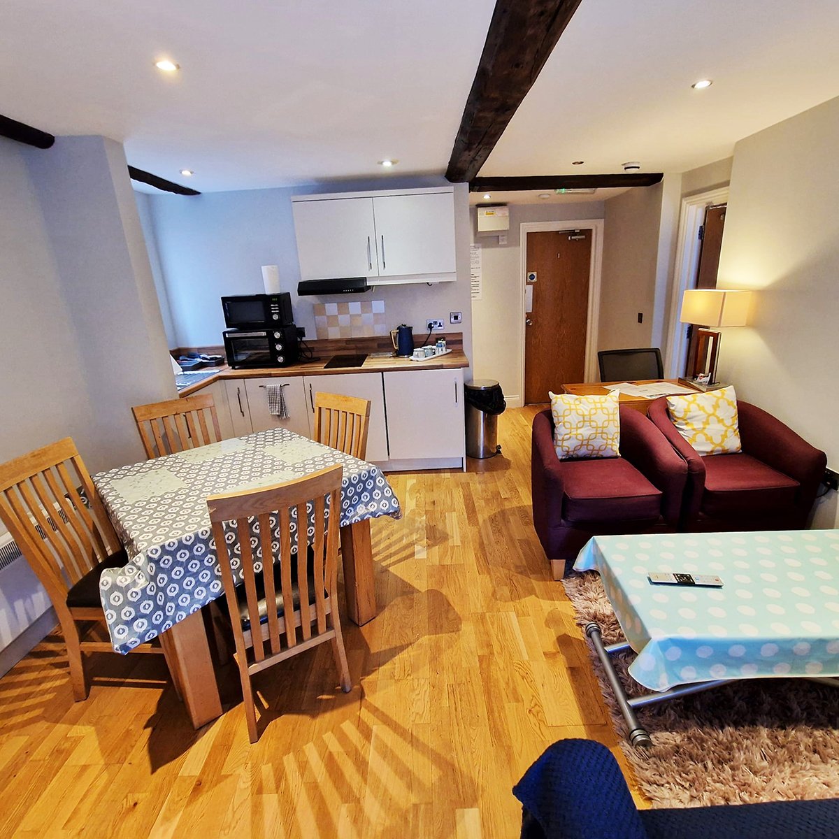 Open-plan living area with kitchen, dining table, sofa, and wooden flooring throughout