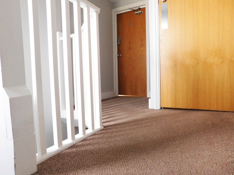 Hallway with brown carpet, white wall dividers, and wooden doors