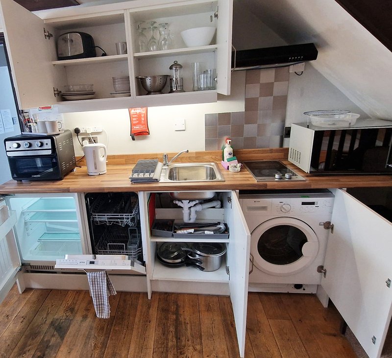 Small kitchen with wooden countertop, open storage cabinets, integrated appliances and sink