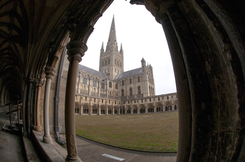 Historic cathedral courtyard with Gothic architecture, arches, columns and green lawn