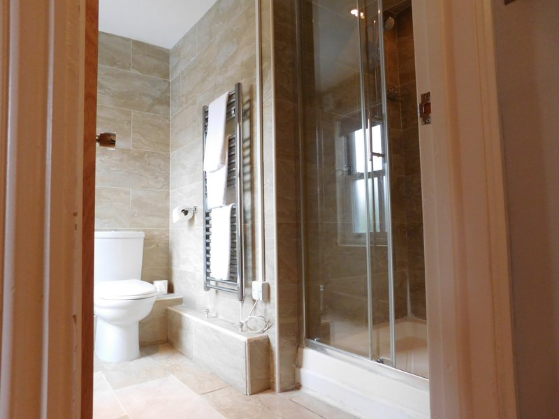 Modern bathroom with walk-in shower, toilet, heated towel rail and marble tiling