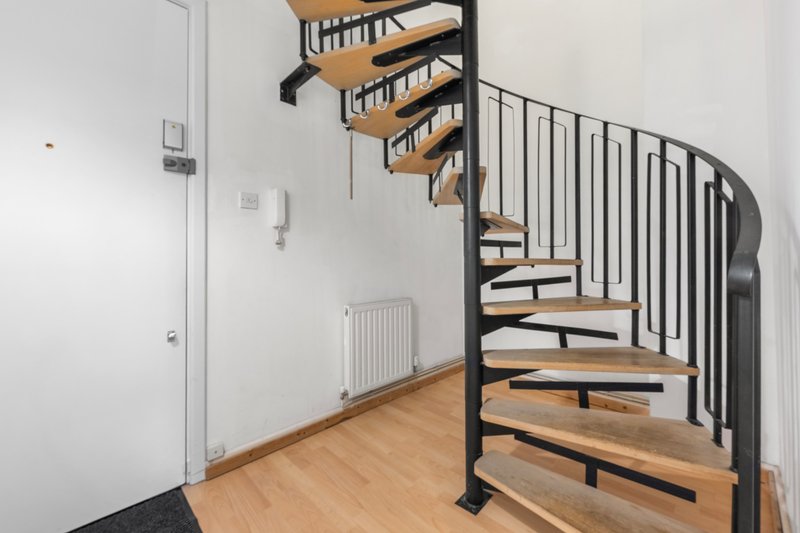 Modern spiral staircase with wooden steps and black metal railings in bright interior space