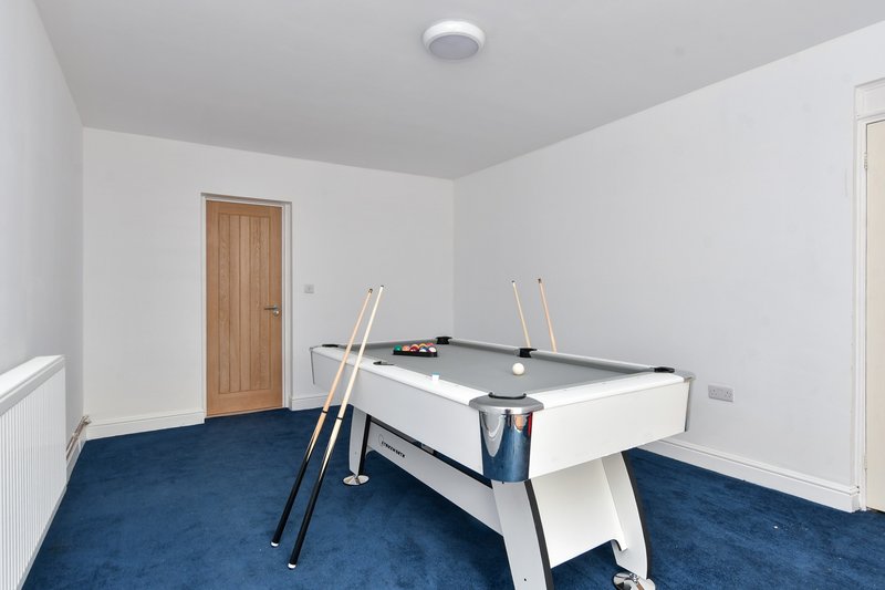 Games room with white and grey pool table, blue carpet, wooden door and recessed ceiling light