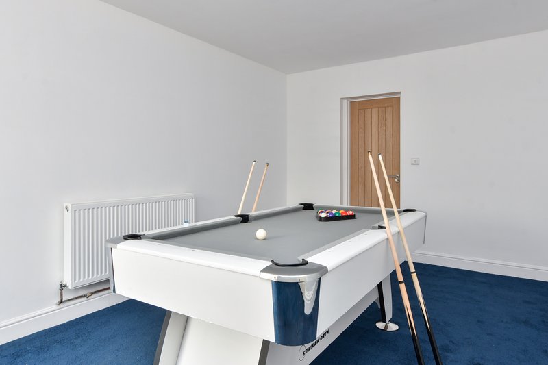 Recreation room with pool table, cues, and blue carpet flooring