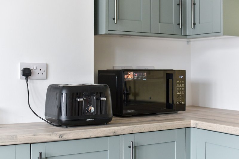 Modern kitchen countertop with black toaster, microwave, and wall outlet