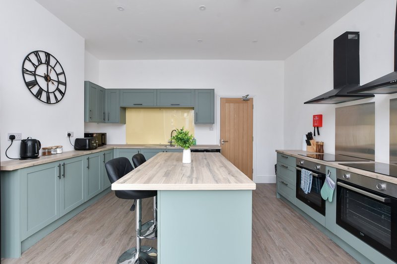 Modern kitchen with light blue cabinetry, wooden island, stainless steel appliances and clock