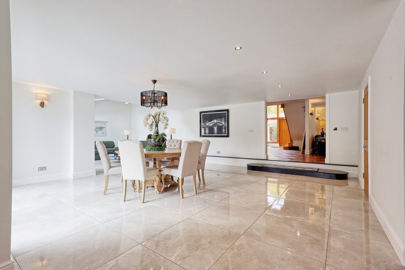 Open-plan living area with dining table, chairs, and polished stone flooring