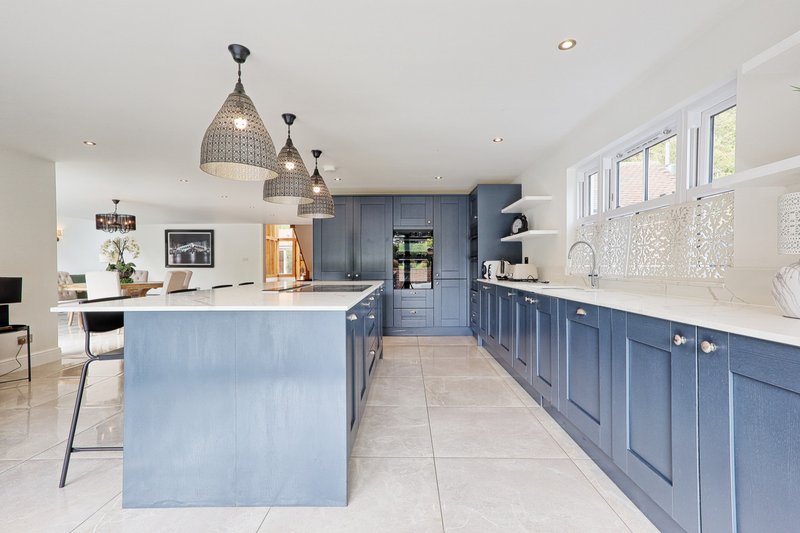 Modern kitchen with blue cabinetry, white countertops, pendant lights and island