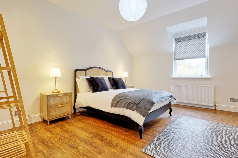 Bright bedroom with double bed, wooden floor, bedside table and window